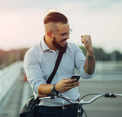 man celebrating with phone in hand while riding a bike