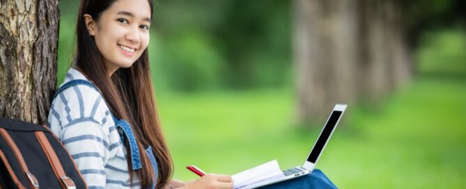 A college student sits in a park working on a project.