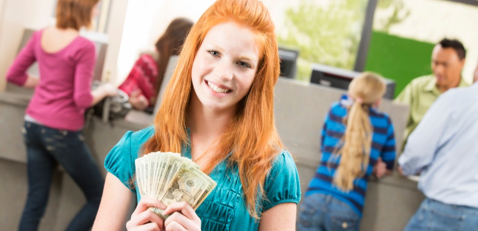 A young teen is about to deposit money at her financial institution.