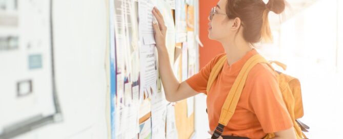 A college student looks at an employment board for a new working opportunity.