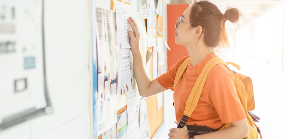 A college student looks at an employment board for a new working opportunity.