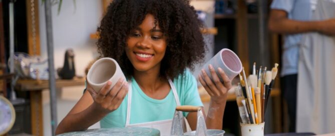 A young woman examines pottery she has made before she puts it up for sale.