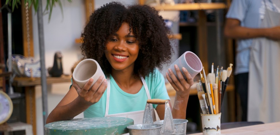 A young woman examines pottery she has made before she puts it up for sale.