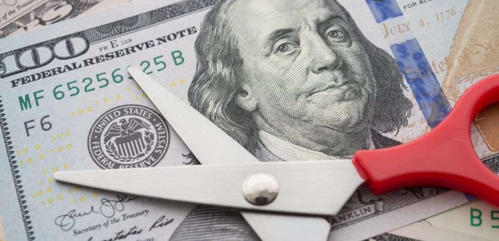 Benjamin Franklin on a $100 bill is threatened by a pair of scissors.