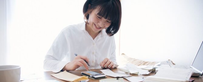 A happy woman works on her finances on her home computer.