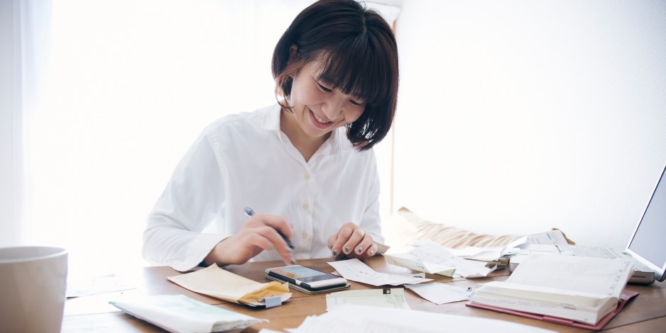 A happy woman works on her finances on her home computer.