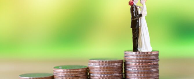 A toy bride and groom stand atop a pile of coins